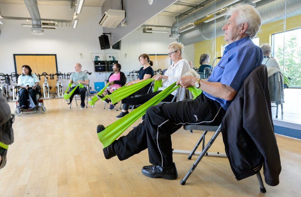 Older people doing chair based exercise with stretching bands