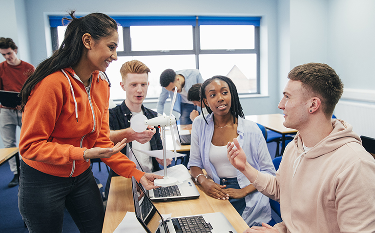 Students sat at tables talking with their tutor