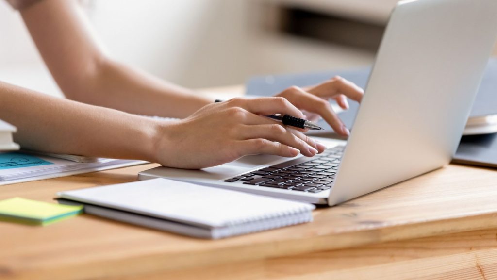 Hands typing on a laptop